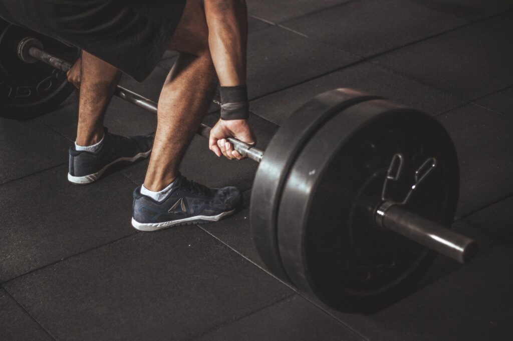 man in black reebok shoes about to carry barbell